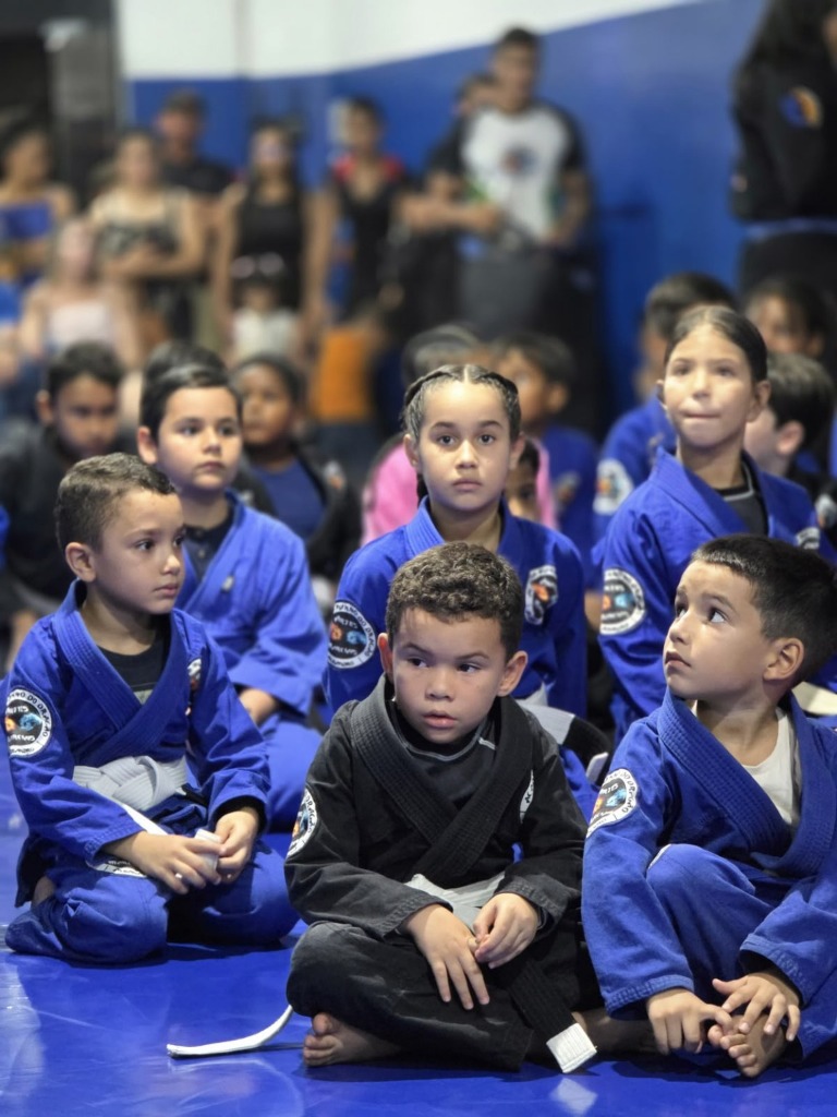 Crianças da turma Punho Kids atentas no tatame durante instrução