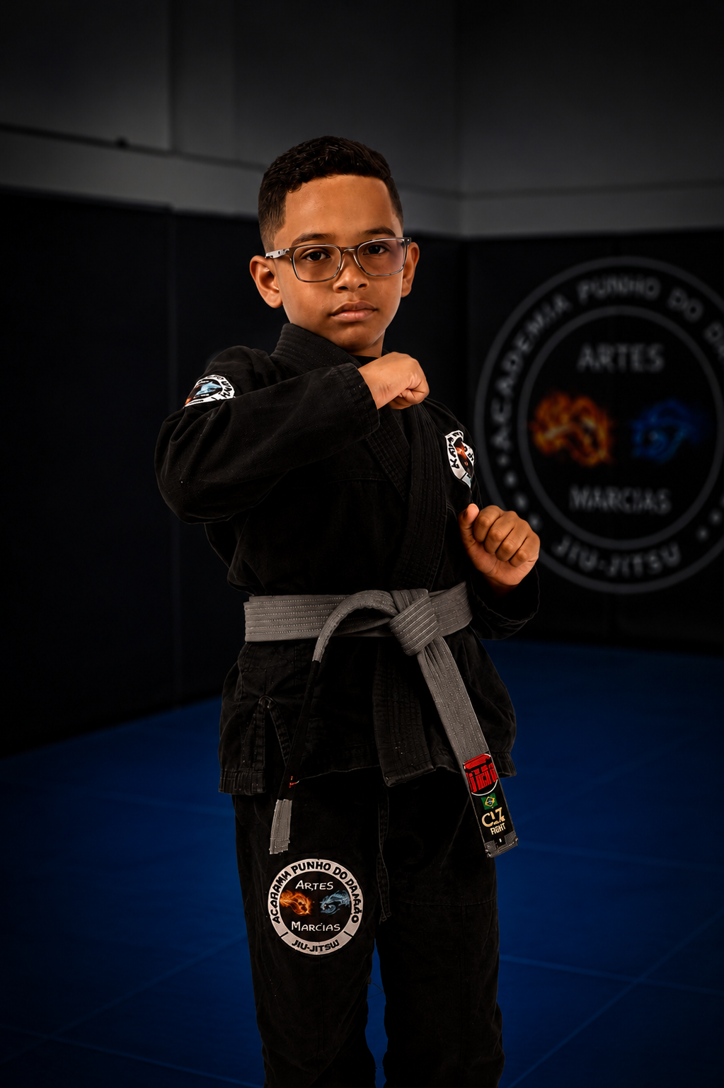 Aluno da turma Punho Kids, de kimono preto e faixa cinza, no tatame da academia